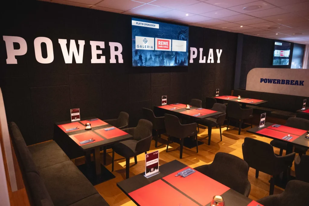 Lounge-Bereich mit Sitzbänken vor der Wand mit dem Schriftzug Power Play