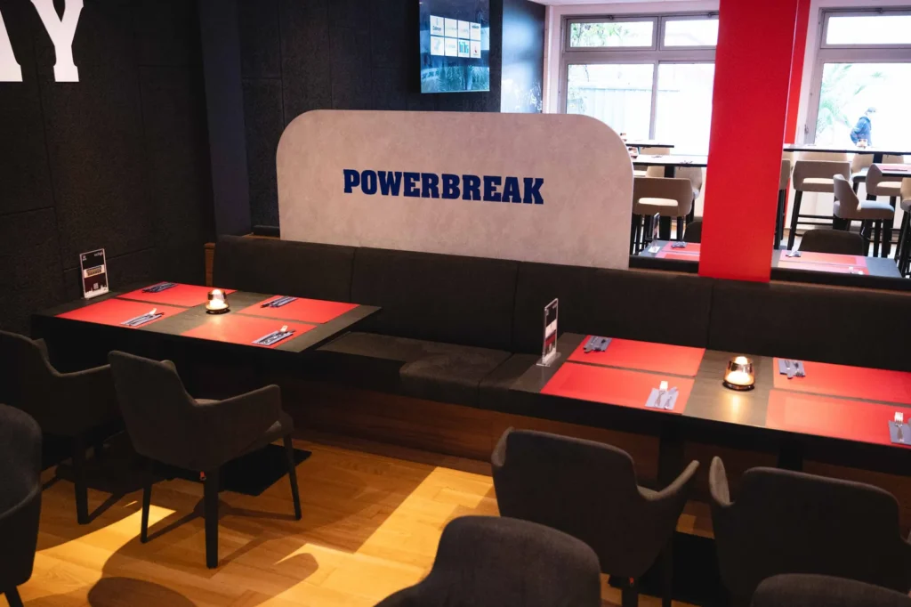 Sitzbänke und Tische vor der Trennwand mit dem Schriftzug Powerbreak
